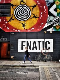 Woman standing on graffiti wall in city