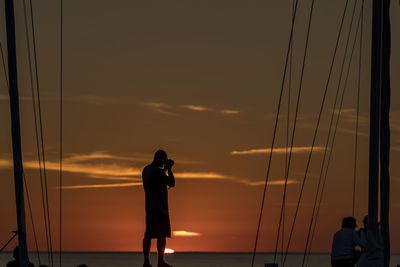 People photographing sea against sky during sunset