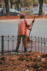 Rear view of man standing by railing against sea