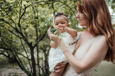 Happy mother and daughter against trees