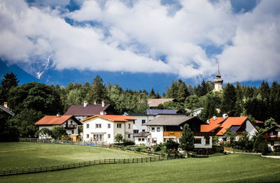 Houses by trees against sky