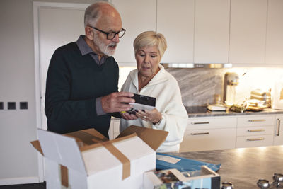 Senior couple unpacking package over kitchen island at home