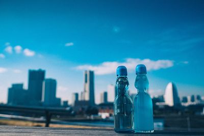 Blue bottle by building against sky