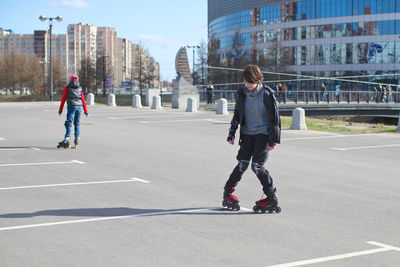 Teenage girl inline skating at parking lot in city