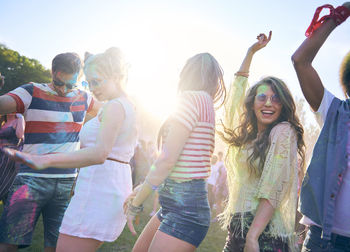 Happy friends dancing at carnival against sky