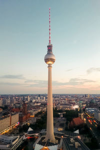 Communications tower in city against sky