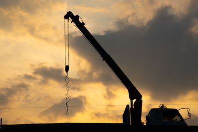 Low angle view of silhouette crane against sky during sunset