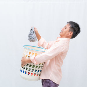 Side view of man holding camera over white background