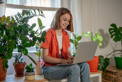 Young woman using laptop while sitting on sofa at home