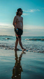 Full length of shirtless man at beach