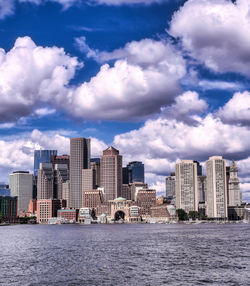 Buildings by sea against sky