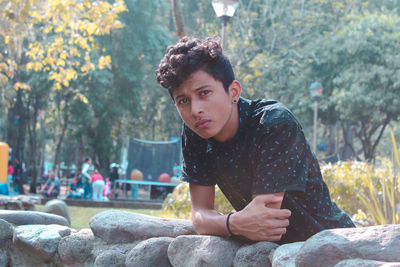 Portrait of young man leaning stone wall