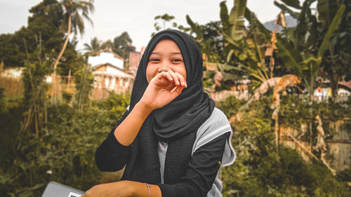 Portrait of smiling woman standing against plants