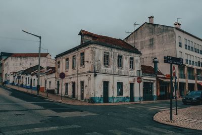 Road by buildings in city against sky