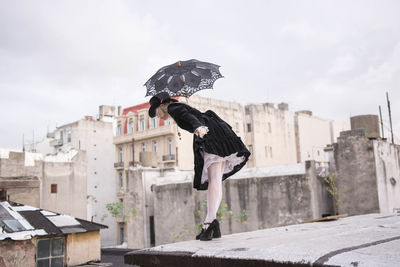 Woman holding umbrella while standing on terrace