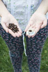 Midsection of woman holding hands on field