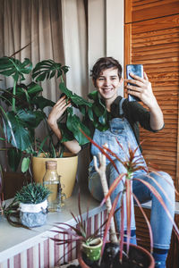 Girl makes photo with smartphone for social media, home plants on balcony, green room, gardening