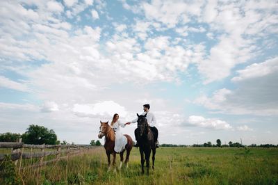 Couple riding horse on field