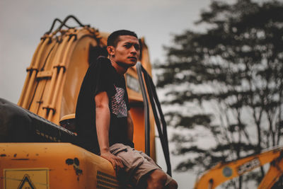 Young man standing on car against sky