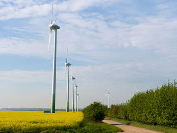 Wind turbines on field against sky