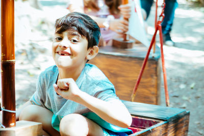 Boy looking away while sitting outdoors