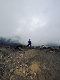 Rear view of man walking on mountain against sky