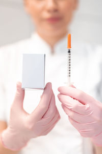 Midsection of doctor holding thermometer