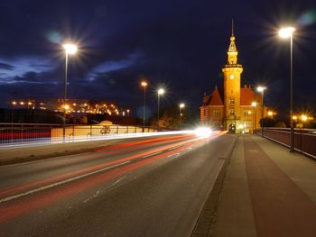 Light trails on road against built structures