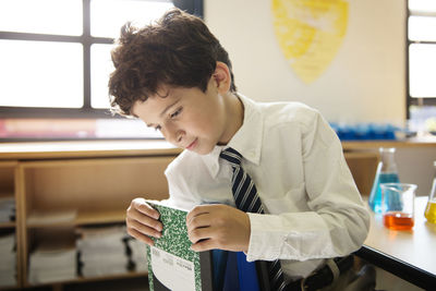 Schoolboy removing book from bag in laboratory