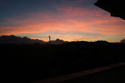 Scenic view of silhouette mountains against orange sky