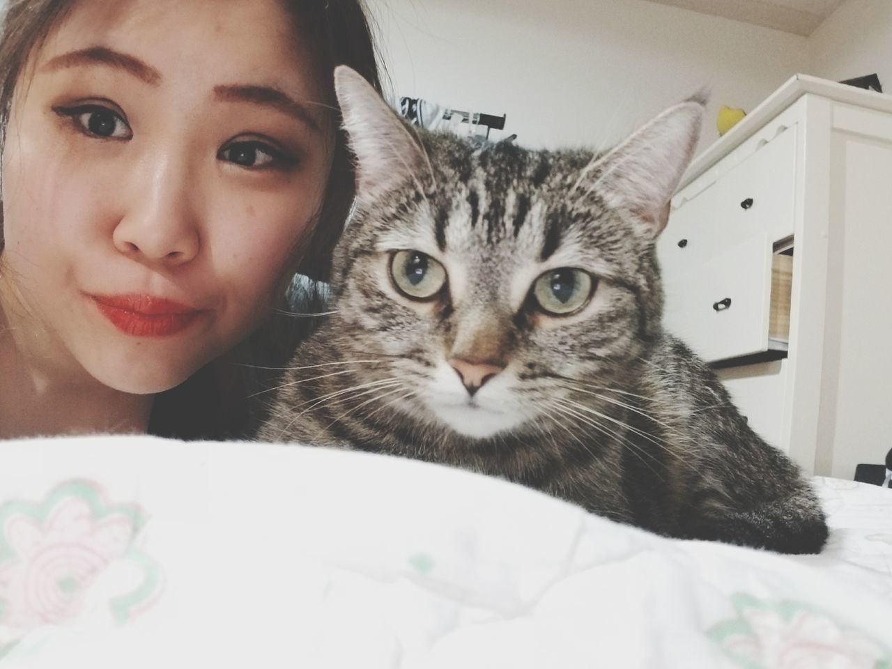 CLOSE-UP PORTRAIT OF YOUNG WOMAN WITH CAT ON BED AT HOME