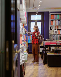 Side view of woman using mobile phone in library