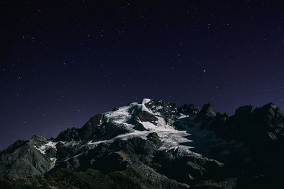 Low angle view of mountains against star field at night