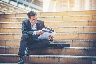 Businessman with documents sitting on steps