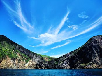 Scenic view of sea and mountains against blue sky