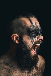 Portrait of a viking warrior with black war paint, screaming with rage and anger