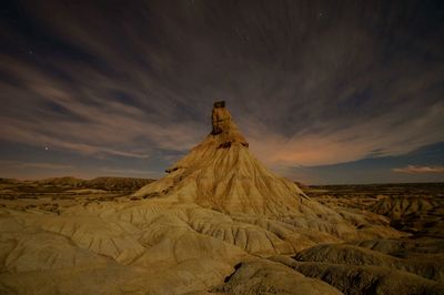 Scenic view of desert against cloudy sky