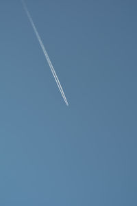 Low angle view of vapor trail against clear blue sky