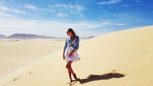 Full length of woman on sand dune against sky