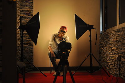 Full length of man sitting on stool against backdrop