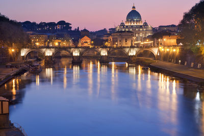 Illuminated bridge over river against sky in city