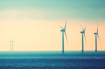 Wind turbines on land against sky