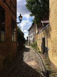 Walkway amidst buildings against sky