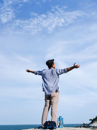 Rear view of man standing by sea against sky