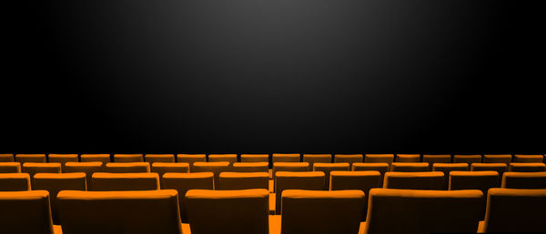 Empty chairs in row against black background