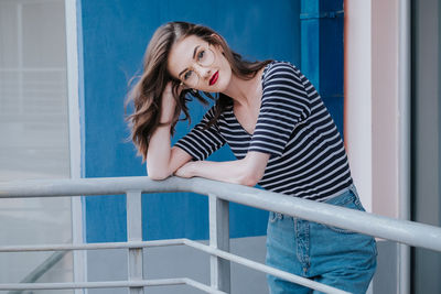 Young woman standing against railing