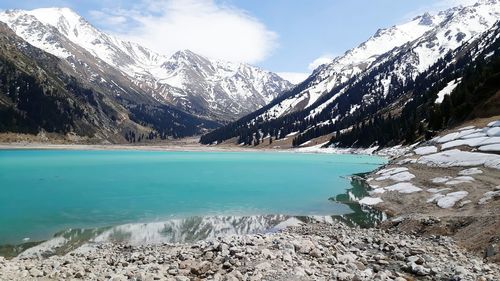 Scenic view of lake by snowcapped mountains against sky