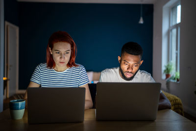 Focused workaholic couple of freelancers work on laptops at home