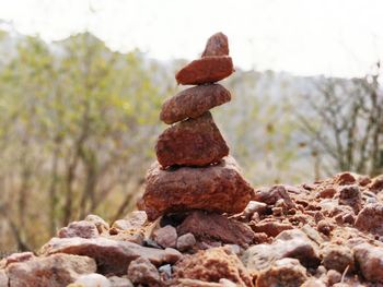 Stack of pebbles on rock against sky