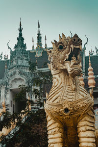 Dragon statue by temple against clear sky
